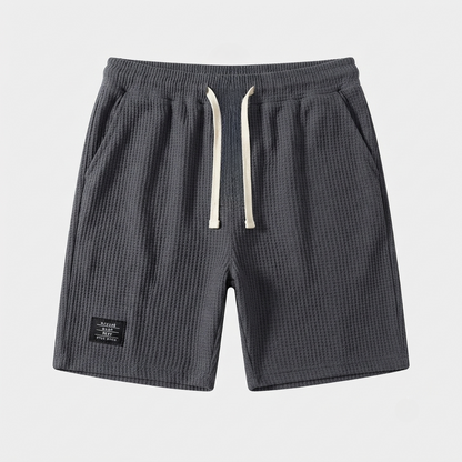 Men's grey waffle shorts with relaxed fit, textured fabric, drawstring waist and side pockets
